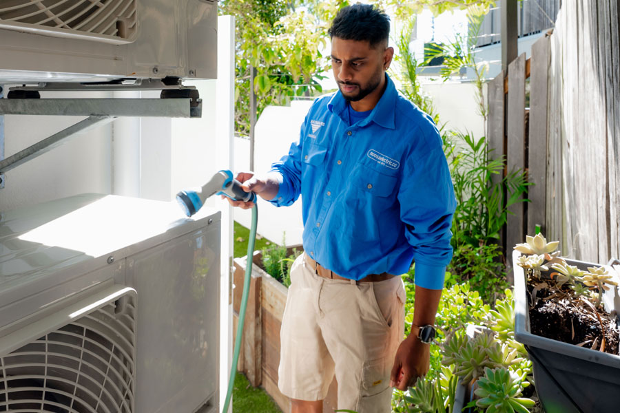 Electrician cleaning outside AC unit
